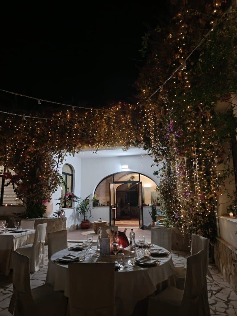Cena in giardino di sera, tavolo apparecchiato sotto le luci alla Masseria Torricella